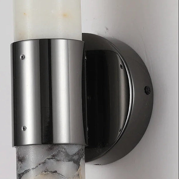 Close-up of stainless steel cylinder and black circular wall mount for sconce