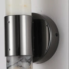 Close-up of stainless steel cylinder and black circular wall mount for sconce