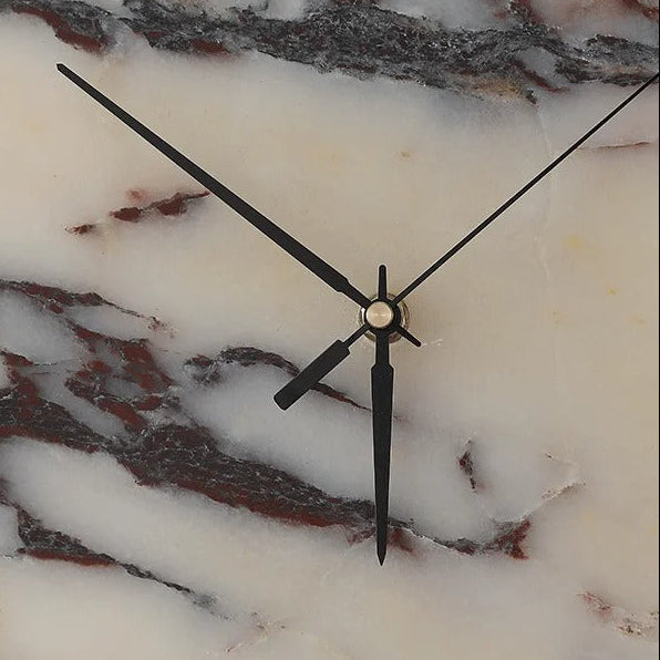Close-up of black clock hands on a marble-pattern round wall light with Roman numerals