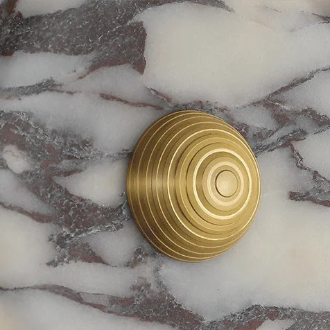 Round backlit wall sconce with gold spiral center and white marble patterned face