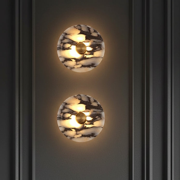 Two round marble wall sconces with warm backlight and gold centers