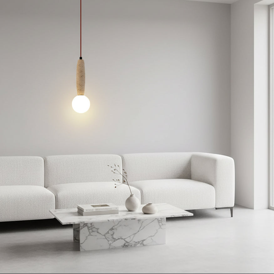 Pendant light with travertine cylinder shade and lit white globe over sofa