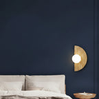 Half-moon travertine wall sconce with lit round white diffuser on wall