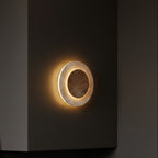 Round backlit wall sconce with glowing oval ring and wood-tone inner disc