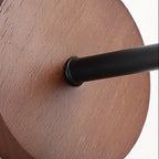 Close-up of black lamp arm attached to round wood backplate
