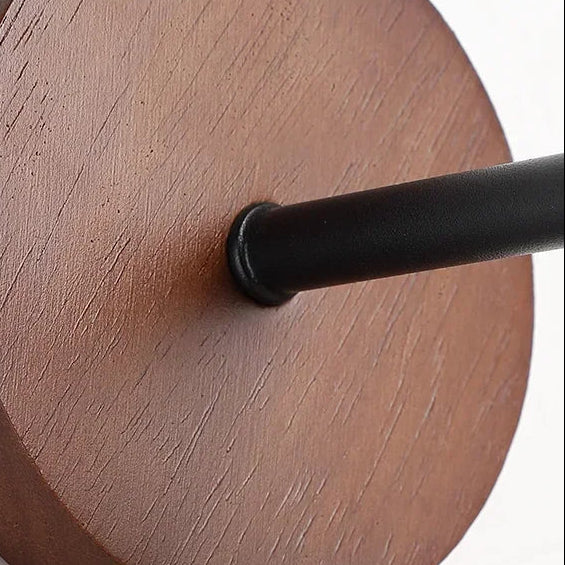 Close-up of black lamp arm attached to round wood backplate