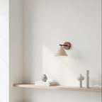 Conical wall light with round wood backplate, black support bar, soft lit shade