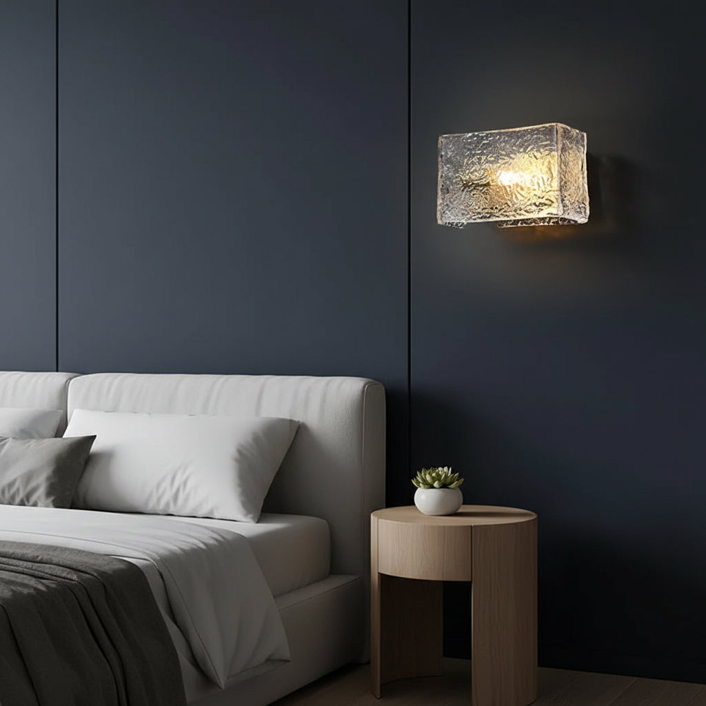 Rectangular ripple glass wall sconce lit on a wall with compact metal fixture