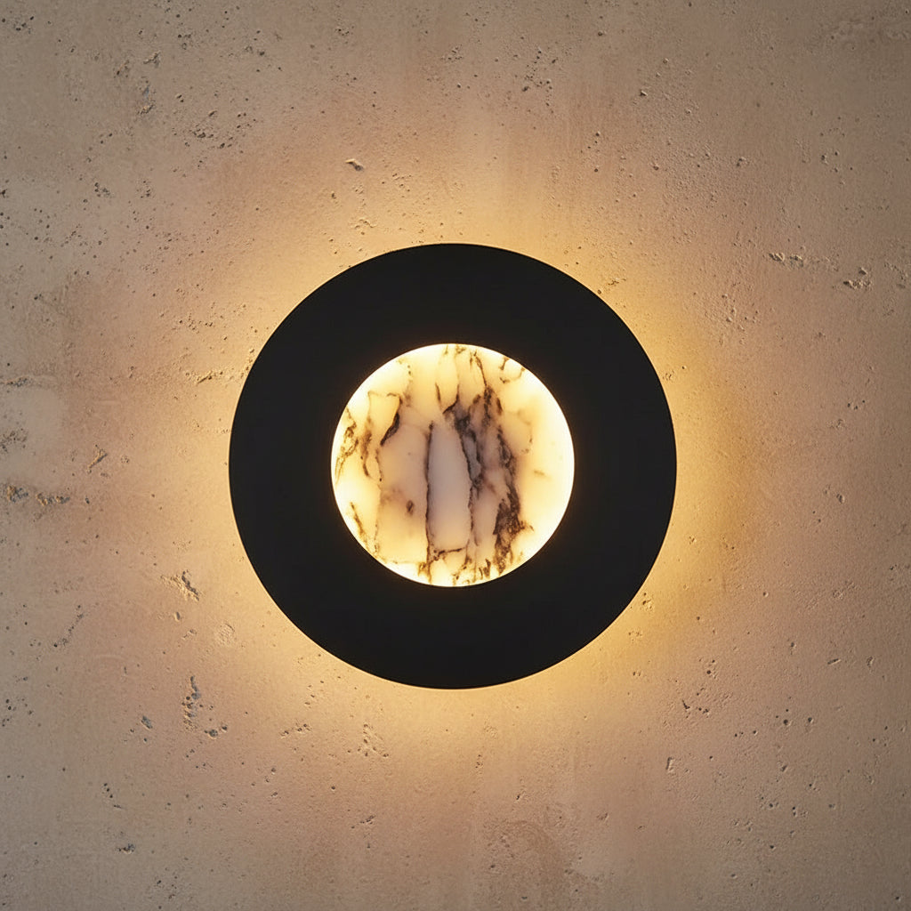 Round black wall light with marble backlit center in warm yellow glow