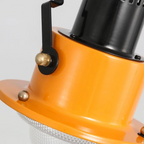 Orange spotlight base with black adjustment arm and knobs on a ceiling mount