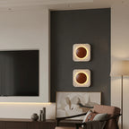 Pair of square travertine wall sconces with backlit circular openings, warm light