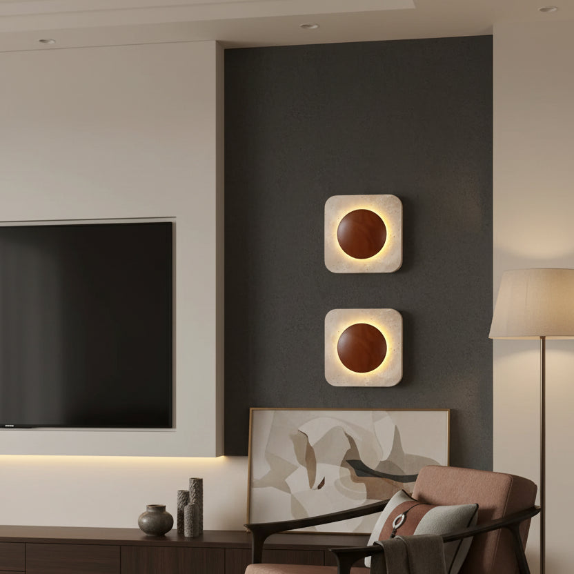 Pair of square travertine wall sconces with backlit circular openings, warm light