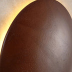Textured circular diffuser of square wall sconce, warm backlit glow around ring