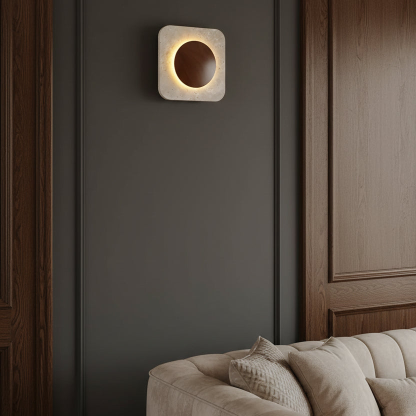 Square travertine wall sconce with backlit circular cutout and warm halo