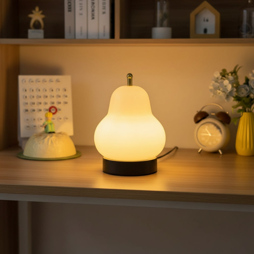 Glowing cream gourd lamp on a desk with gold top and black base.