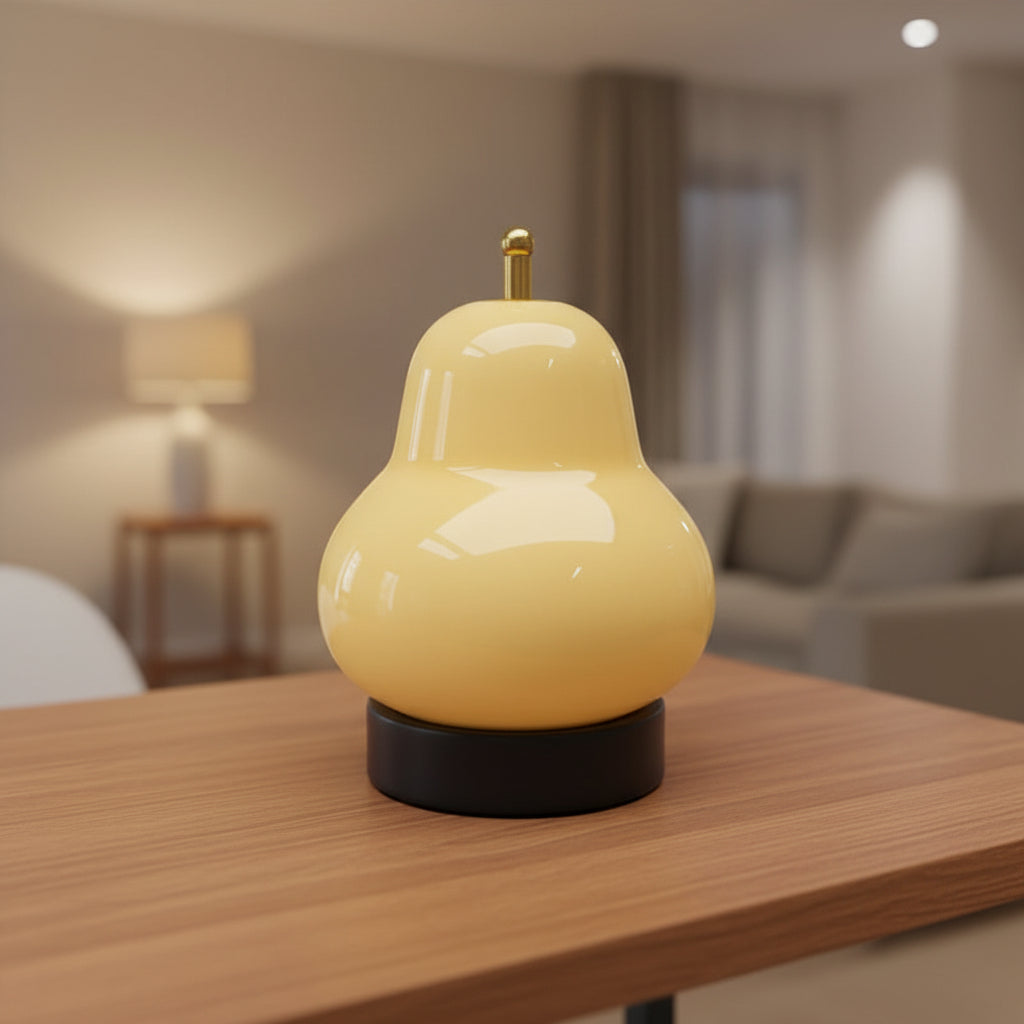 Cream gourd-shaped lamp glowing with gold top and black base on table.