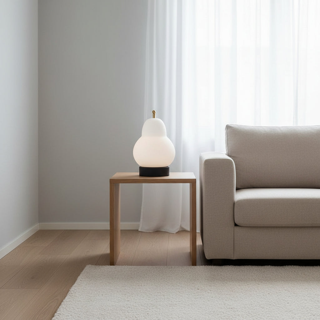 Small white gourd portable table lamp with gold top on a side table.