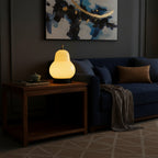 Cream gourd-shaped portable lamp glowing on a nightstand with black base.