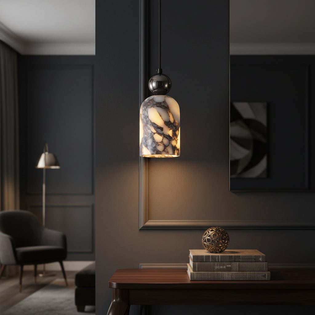 Marbled glass pendant light with warm yellow glow and dark metal top, above table.