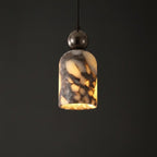 Marbled glass pendant shade with warm yellow glow, dark metal top, suspended on cord.