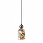 Marbled glass pendant shade with warm yellow glow, dark metal top, single hanging.
