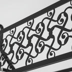 Black metal scrollwork cage panel detail on a long ceiling light fixture