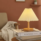 Pleated conical table lamp with warm white pleated shade and light wood base