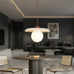 Globe pendant light hanging on a red cord, speckled travertine disc and off-white globe