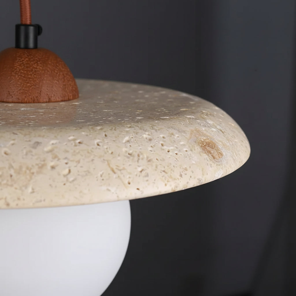 Close-up of travertine disc shade and off-white glass globe on pendant light