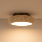 Round travertine ceiling flush mount light with speckled stone shade and warm glow