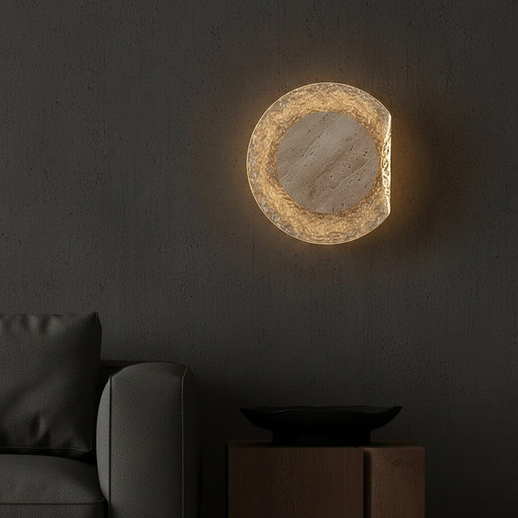 Round travertine disc wall light glowing warm amber in textured light-gray ring