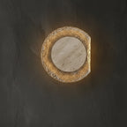 Round travertine disc wall light with bright warm-amber glow around pale stone insert