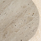 Close-up of travertine disc wall light with speckled beige stone texture