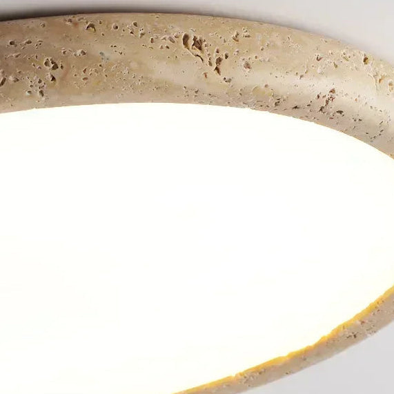Travertine-look ring detail around a flush ceiling light with warm light glow