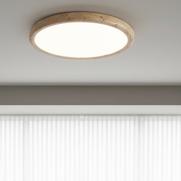 Round flush mount ceiling light with travertine-style ring, emitting soft light upward